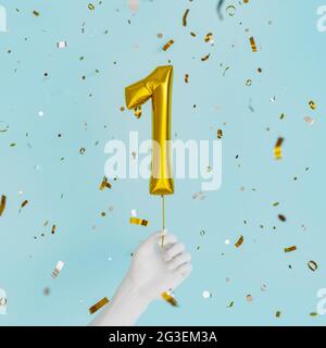 white hand holding a balloon with the number 1 and golden confetti falling down. birthday celebration. 3d render Stock Photo