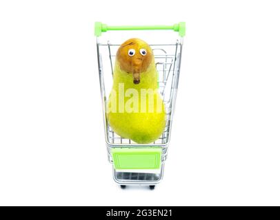 Close-up of a cute character made from a fresh pear in a toy shopping cart isolated on white background. Stock Photo