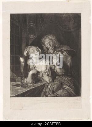 Man and woman with needle and thread. A man and a woman in an interior by candlelight. The man sticks a thread through the needle that the woman holds. The woman has a sewing cushion on her lap. Stock Photo