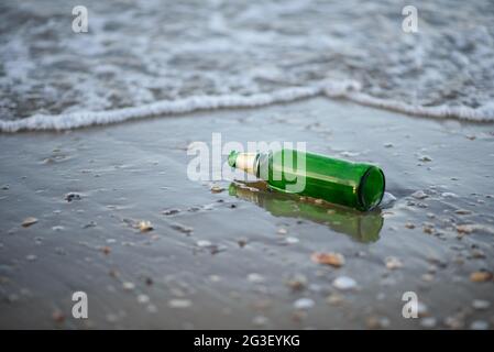The green glass bottle waste on the beach. Stock Photo