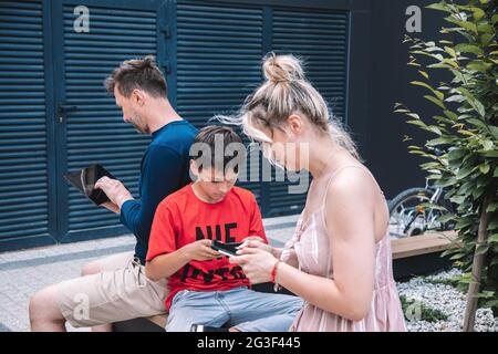Modern generation of people using smartphones. Family uses smartphones for walk in . city on weekend summer day. High quality photo. Lifestyle Stock Photo