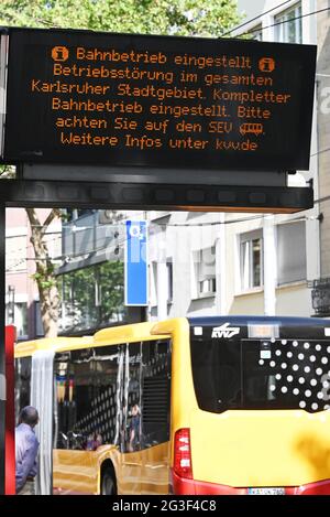 16 June 2021, Baden-Wuerttemberg, Karlsruhe: At a tram stop in Karlsruhe city centre, a digital information board indicates that rail service has been suspended. In the background, a bus can be seen that is in use as a rail replacement service. The trams and light railways in Karlsruhe will not be able to run regularly on Wednesday due to damage to the rail network. Therefore, an emergency concept is in effect for the time being. Already on Tuesday, all tram and light rail traffic had been suspended. According to a spokesman for the transport company, the reason was damage to several rail line Stock Photo