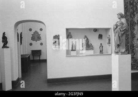 Room with various objects including images in showcases and on pedestals and a passage; Interiors West, setup in the early 1950s. . Stock Photo