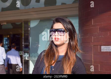 A pretty Asian woman wearing sunglasses with a smile standing outside in the street, fashion concept. Stock Photo