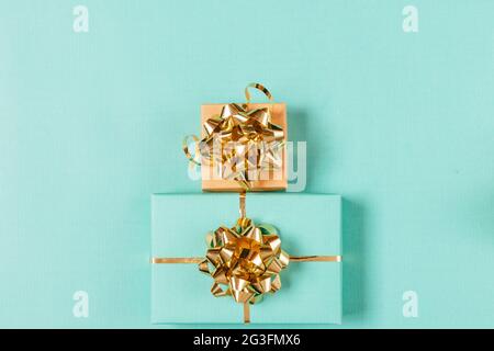 Festive gift boxes with golden ribbons and bows on turquoise background, flat lay arrangement. Stock Photo
