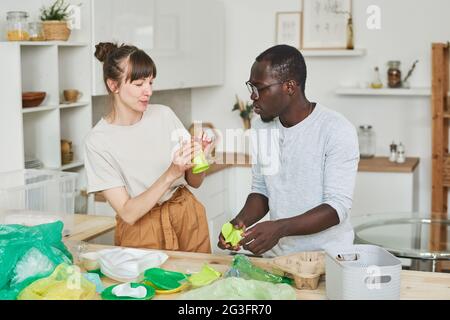 Young couple sorting the rubbish together in the kitchen at home Stock Photo
