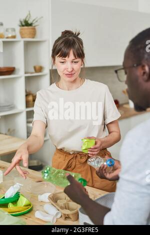 Young couple sorting the garbage in packets together standing in the kitchen Stock Photo