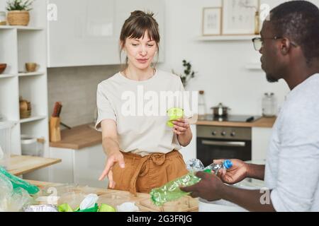 Woman helping man to sorting garbage in the kitchen at home Stock Photo