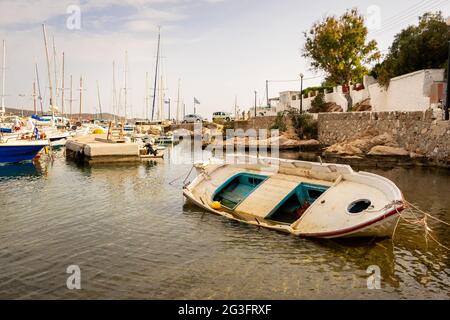 Old wooden fishing boat aground in Finikas Marina, Greece, with sailing boats in the background. Stock Photo