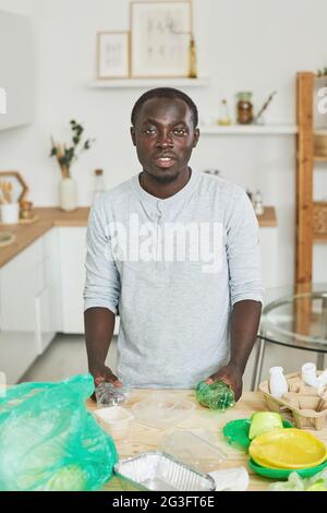 Portrait of African man looking at camera while sorting plastic in the kitchen Stock Photo