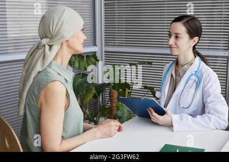 Portrait of young female doctor talking to patient during consultation in medical clinic, copy space Stock Photo