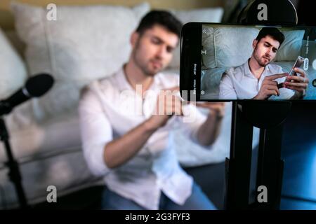 Young male recording video broadcast from home studio setup Stock Photo