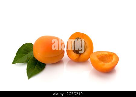 Whole apricot with leaves and one cut in half with the seed, isolated on white Stock Photo