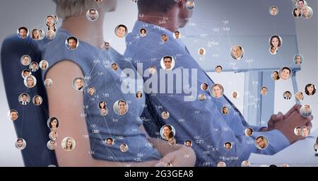 Network of profile icons against mid section of businessman and businesswoman at office Stock Photo