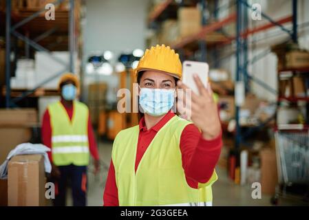 Cheerful warehouse worker taking selfie with smartphone Stock Photo