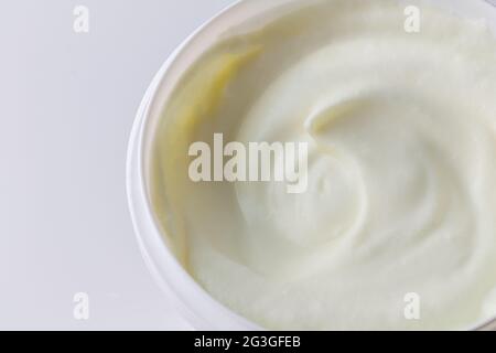 White yogurt in large plastic container close up on white with space for text - Greek yoghurt background Stock Photo