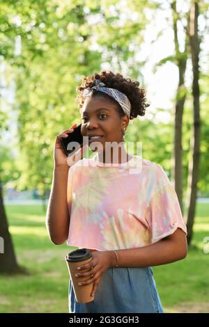 African young woman talking on mobile phone while standing outdoors Stock Photo