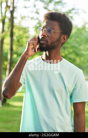 African young man talking on mobile phone while standing outdoors Stock Photo