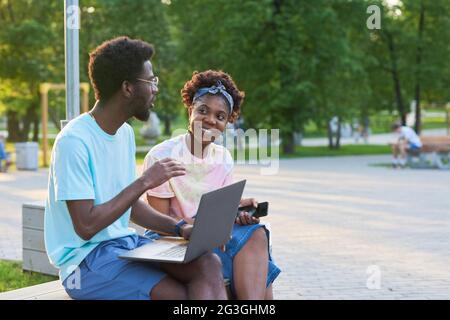 African young couple working on laptop together during their meeting in the park Stock Photo