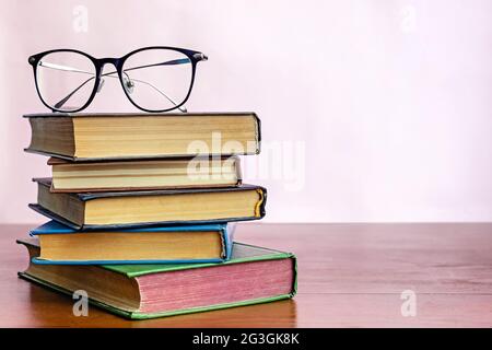 Stack of books with reading glasses on top Stock Photo