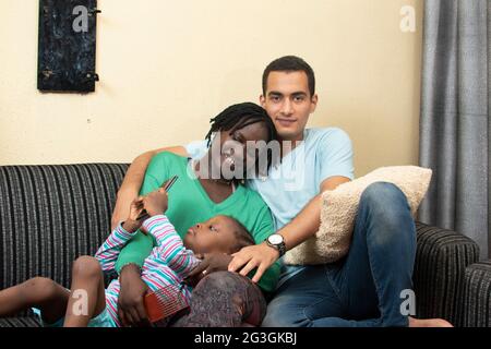 pleasant mixed race couple and their baby child using smart phone Stock Photo