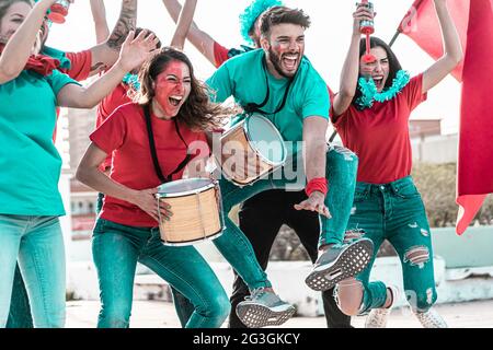 Crazy sport fans playing drums, jumping and screaming while supporting their team. Football Event concept. Stock Photo