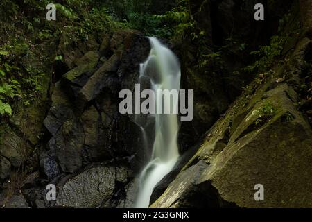 Pria Laot waterfall, hidden between rocks, moss and surrounding rainforest, in the central area of Pulau Weh island, Sumatra, Indonesia Stock Photo