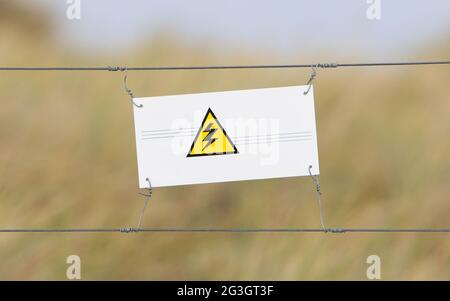 Border fence - Old plastic sign with a flag Stock Photo