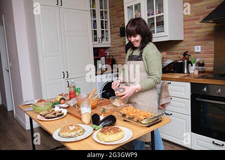 A couple of friends laughing and cooking. Cooking mediterranean and healthy food. Stock Photo