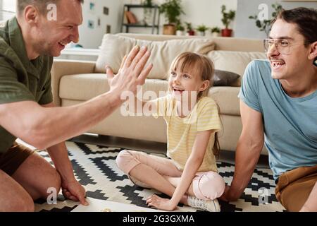 Happy father giving high-five to his child while they playing on the floor in the room Stock Photo