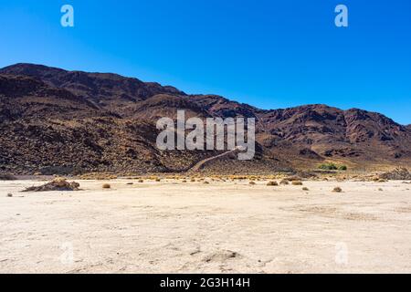 Dark brown desert mountain with hiking trail in the Mojave Desert Stock Photo