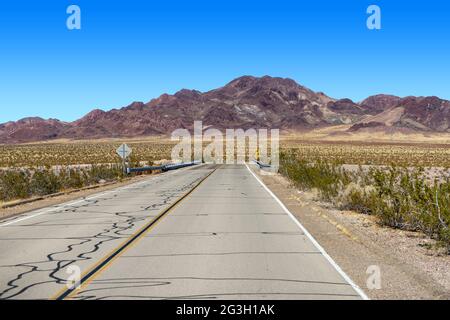 Route 66 in the Mojave Desert near Ludlow with a view of brown desert mountains Stock Photo