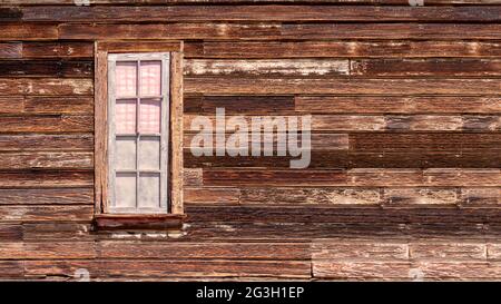 Old western style rustic wooden exterior wall with a framed window Stock Photo