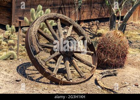 Wagon wooden wheel in a desert landscape with cactus plants Stock Photo