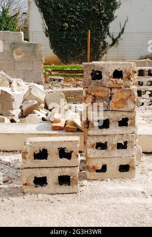 A pile of breezeblocks on a small domestic contruction site. The remains of breezeblock farmhouse are in the background. In Udine Province, Italy Stock Photo