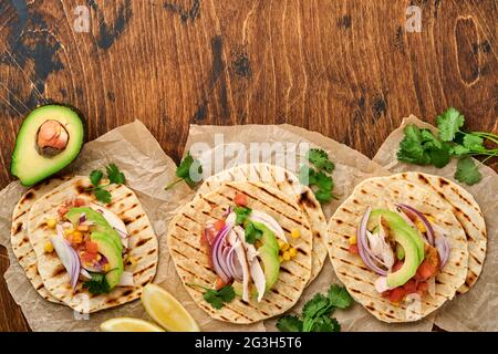 Mexican tacos with grilled chicken, avocado, corn kernels, tomato, onion, cilantro and salsa old wooden table. Traditional Mexican and Latin american Stock Photo