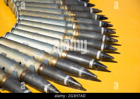 Number of cartridges from machine gun folded in a semicircle on a yellow background Stock Photo