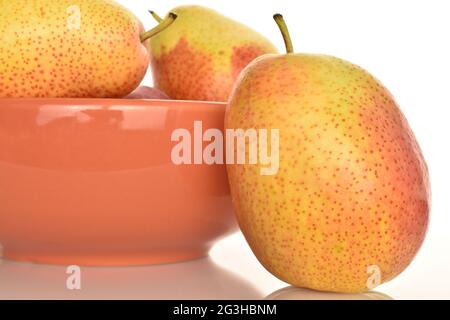One organic yellow-red pear in focus, with ceramic plate, over white background. Stock Photo