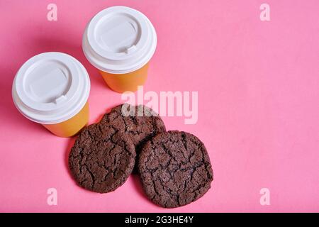 Two glasses takeaway coffee and an American cookie on pink background Stock Photo