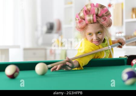 Portrait of a cute little girl playing billiard Stock Photo