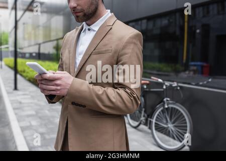 cropped view of bearded businessman using smartphone outside Stock Photo