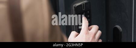 cropped view of man pressing button on intercom keypad, banner Stock Photo