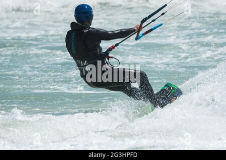 kitesurfer or kite boarder, rear facing, holding onto a control bar while riding the waves during Red Bull King of the Air competition in Cape Town Stock Photo