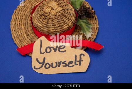 Love yourself hand written note with lady cap in background. Stock Photo