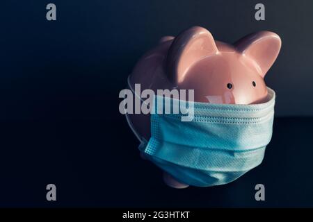 Global economy during coronavirus pandemic. Piggy bank wearing surgical face mask. Financial crisis, banking concept. Stock Photo