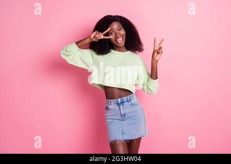 Photo of attractive happy dark skin woman make v signs wear denim skirt smile isolated on pastel pink color background Stock Photo Alamy