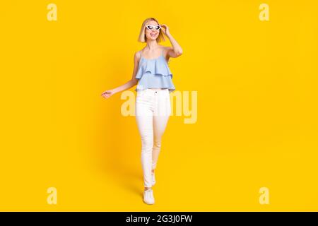 Full size photo of pretty blond short hair lady go wear spectacles top pants isolated on yellow color background Stock Photo