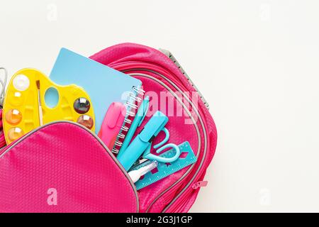 Pink backpack with stationery on white background. Back to school. Stock Photo