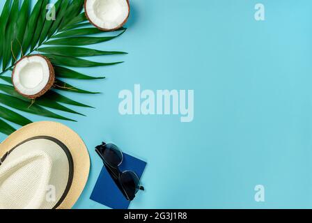 Traveler accessories, coconut and palm leaf on blue background. Flat lay, copy space. Stock Photo