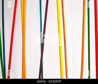 Colored dowels hang against a white background. Stock Photo